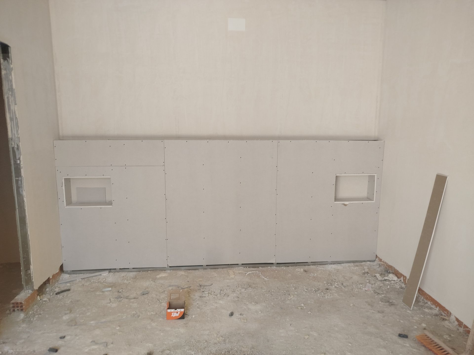 Una habitación con suelo de hormigón y una pared blanca.