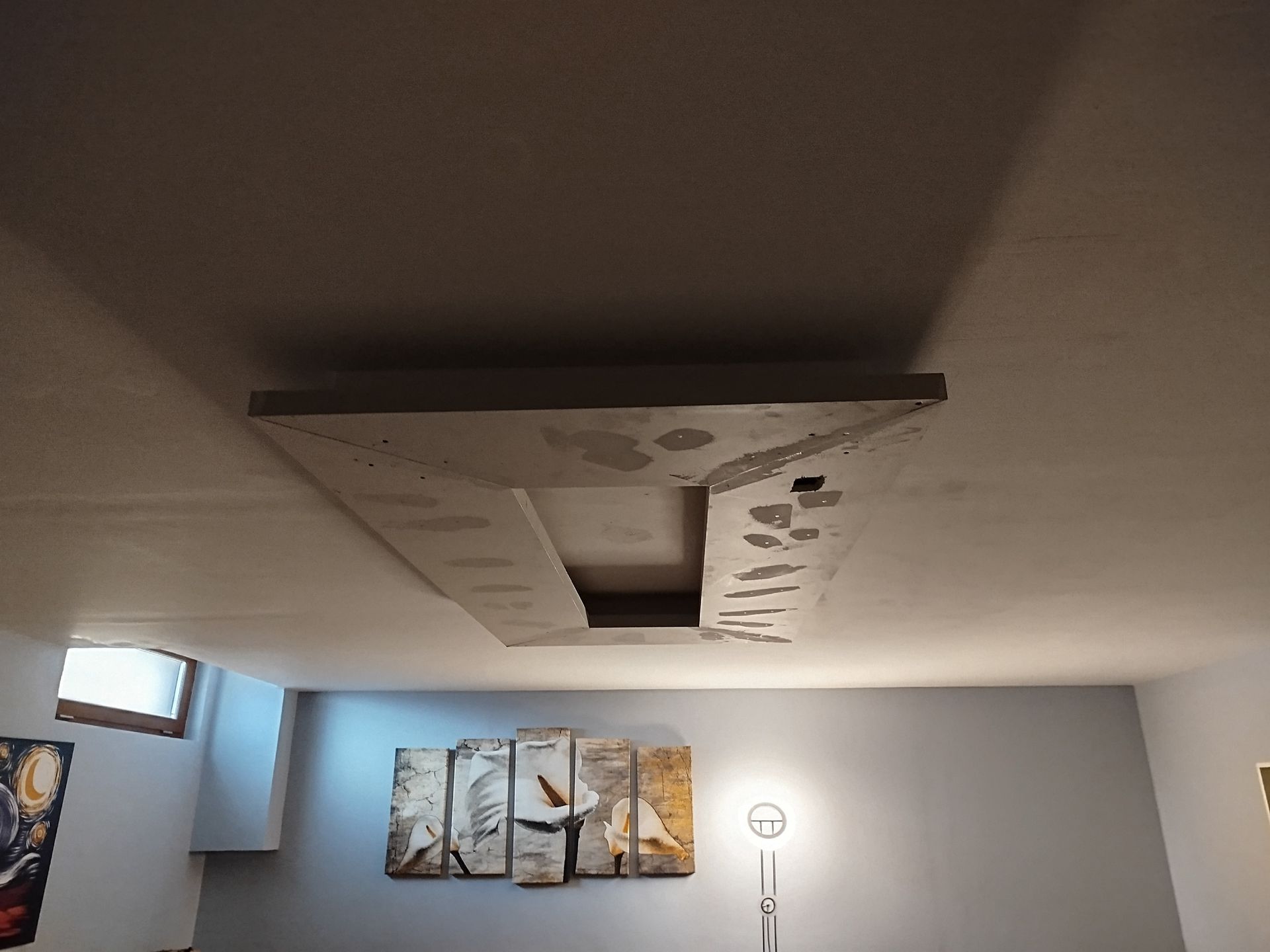 Una habitación con un cuadro en la pared y una lámpara en el suelo.