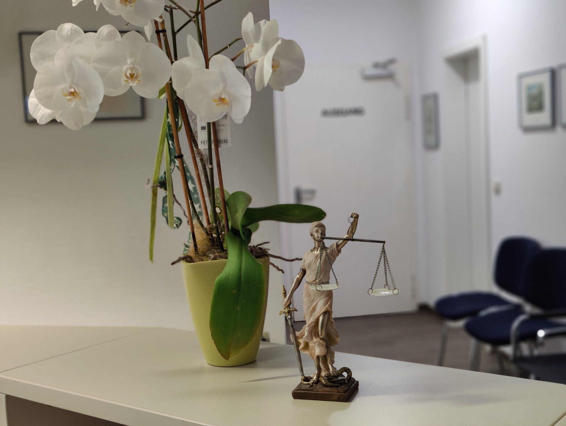 Eine Statue der Gerechtigkeit steht auf einem Tisch neben einer Vase mit Blumen.