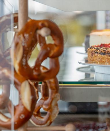 Brezeln hängen in einer Vitrine; Kuchen stehen in Regalen.
