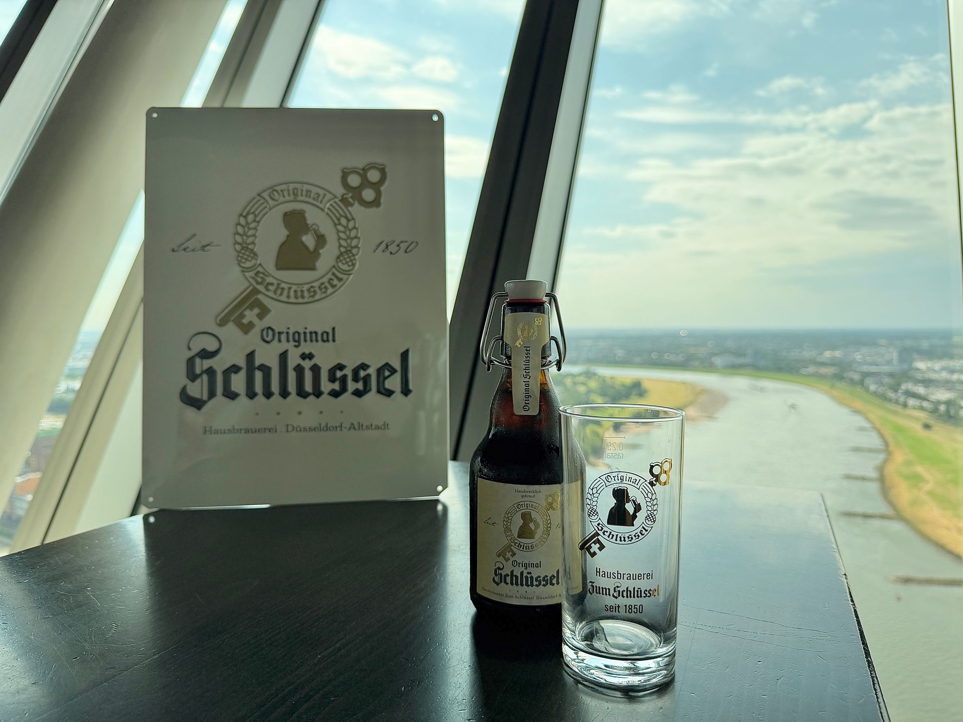 Ein Tisch in einer Bar mit Bier, Fladenbrot und Speisekarte, mit Blick auf die Stadt von einem hohen Gebäude aus.