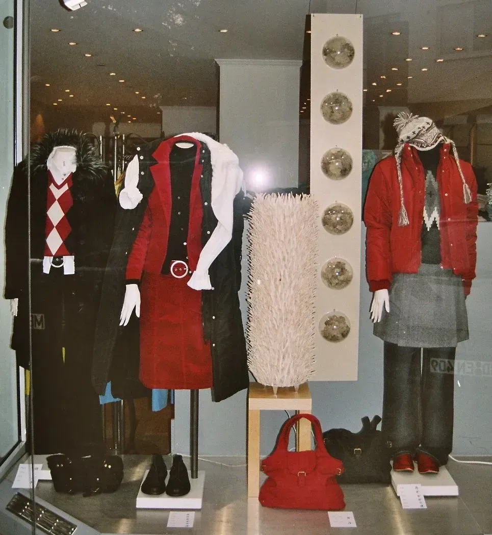 Eine Kleiderausstellung in einem Schaufenster, darunter eine rote Jacke