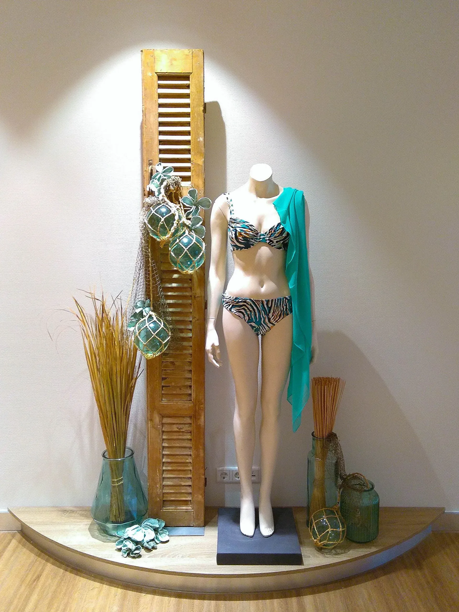 Eine Schaufensterpuppe mit Bikini und grünem Schal
