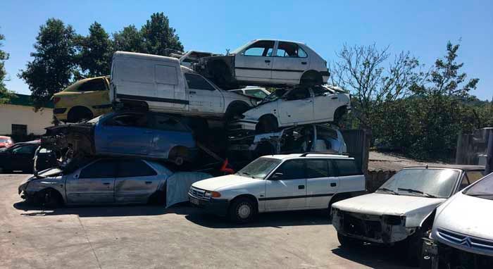 Un montón de coches están apilados uno encima del otro en un estacionamiento.