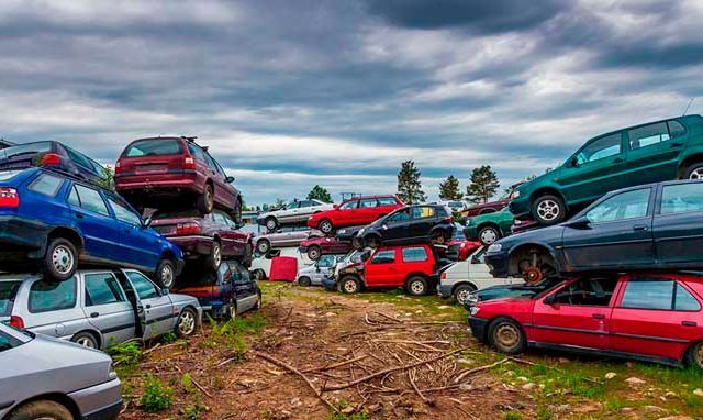 Un montón de coches están apilados uno encima del otro en un campo.