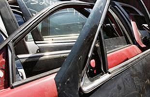 Un coche rojo con una puerta negra está encima de una pila de otros coches.