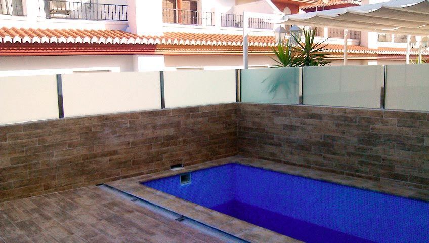 Una piscina con una valla de cristal a su alrededor.