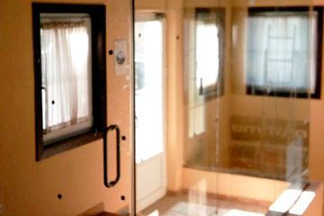 Una habitación con una puerta de cristal y dos ventanas.