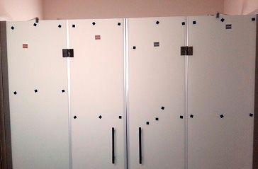 Una fila de armarios blancos con tiradores negros en una habitación.