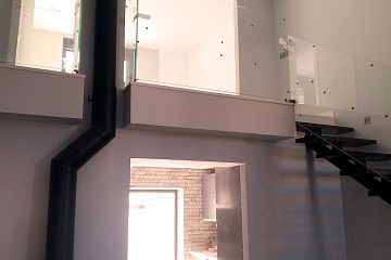 Una escalera con barandilla de cristal que conduce al segundo piso de una casa.