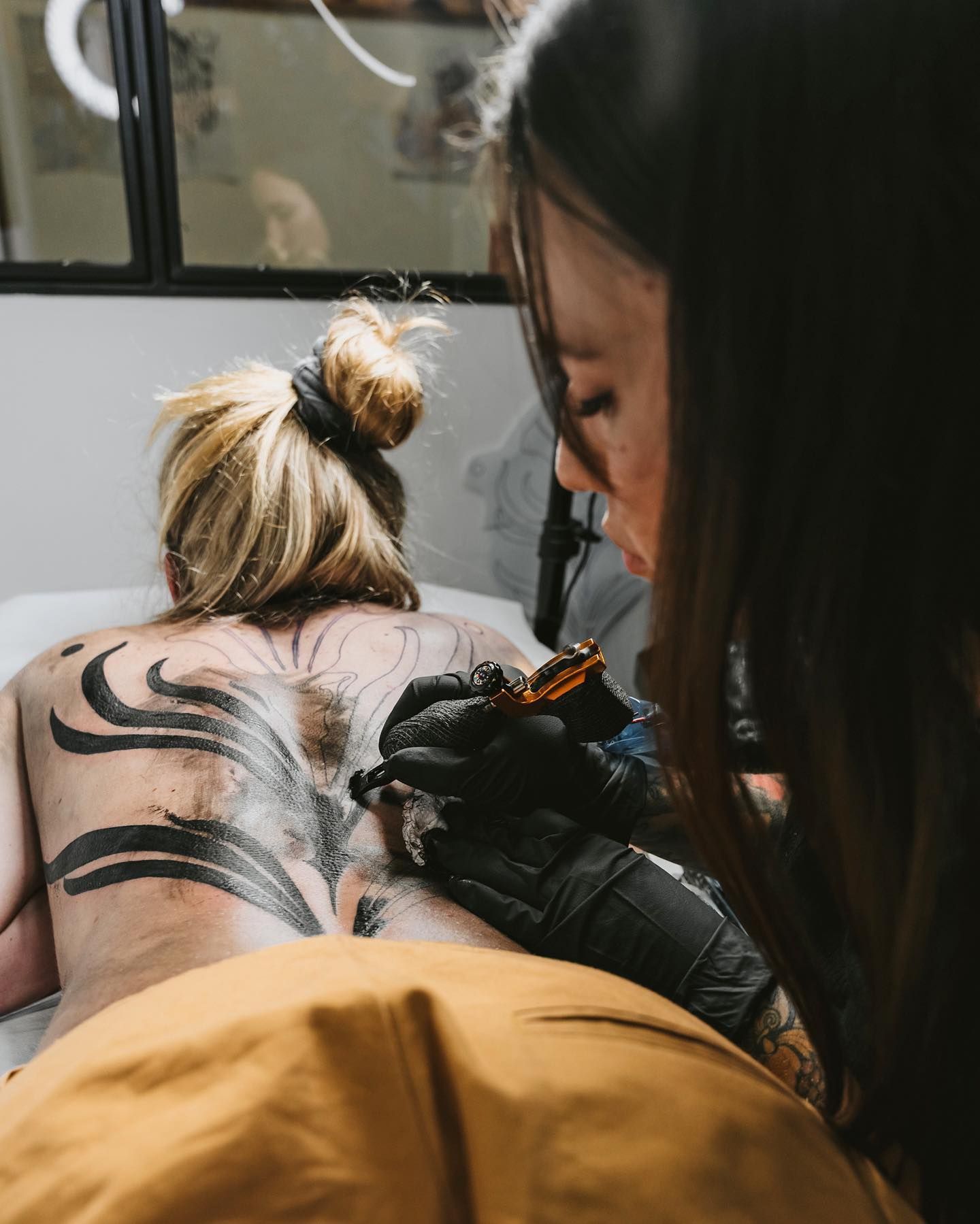 Una persona que recibe un tatuaje en la espalda de un tatuador.