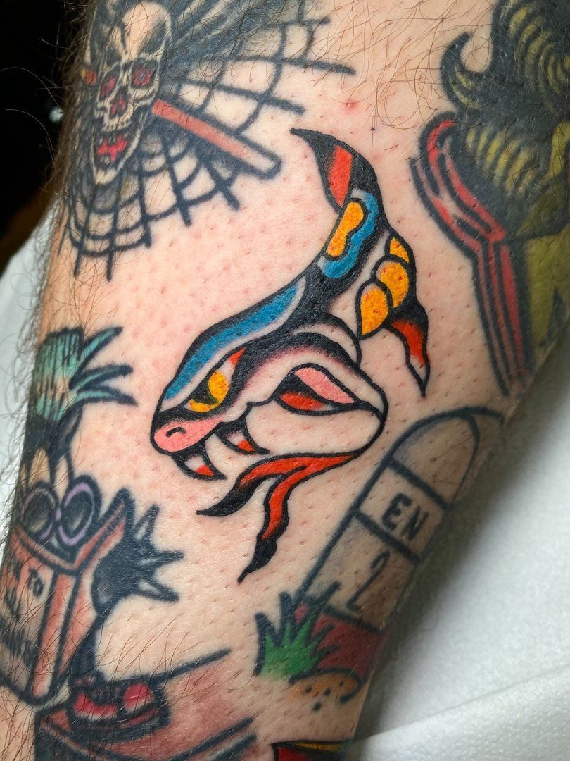 Tatuaje de una serpiente con diseño azul y amarillo en un antebrazo.