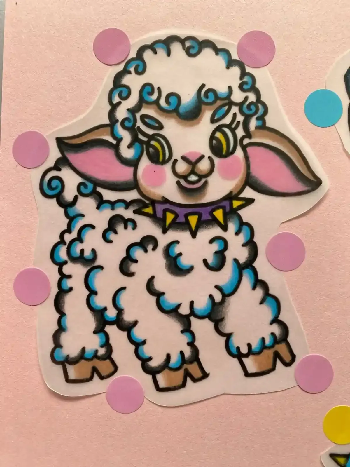Cordero de dibujos animados con lana rizada azul y blanca, con un collar de púas de color morado, sobre papel rosa.
