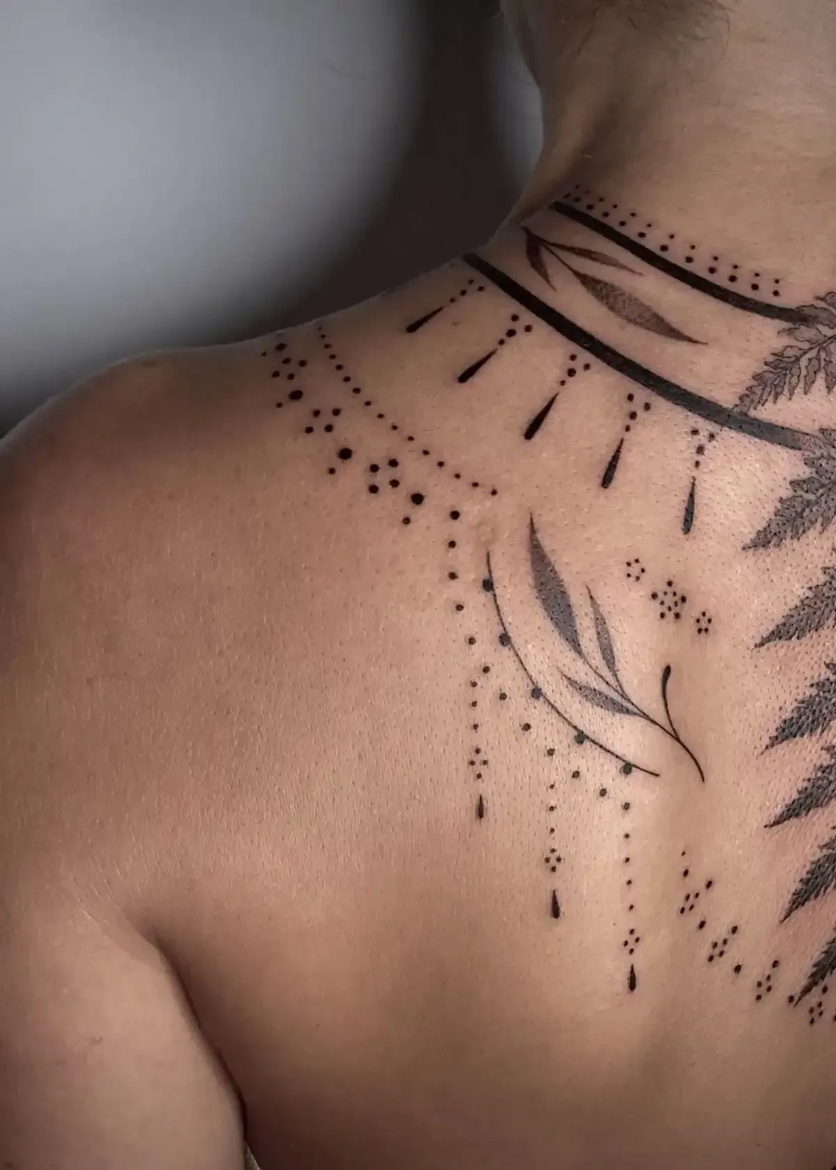 Tatuaje en la espalda; intrincado diseño de tinta negra en el hombro y la parte superior de la espalda.