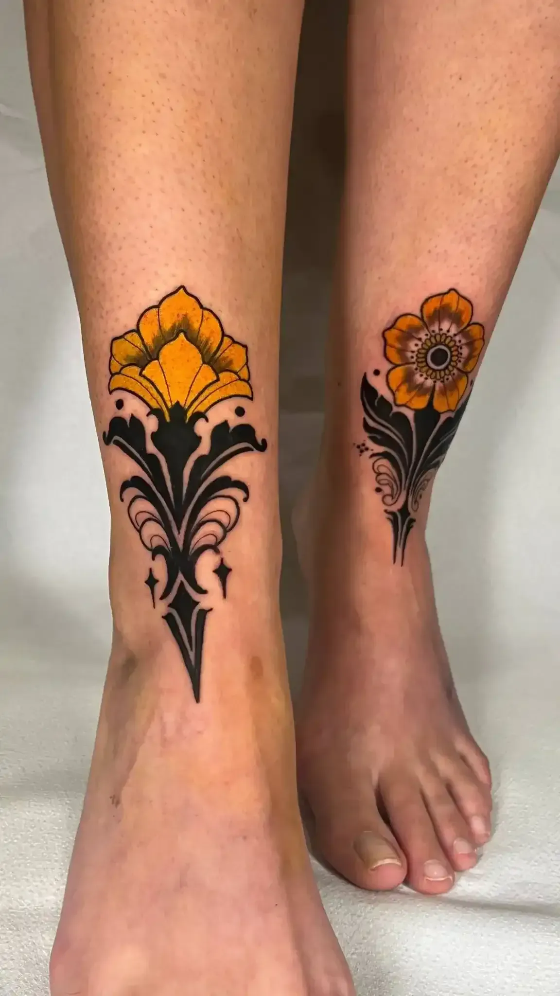 Dos tobillos con tatuajes florales amarillos y negros.