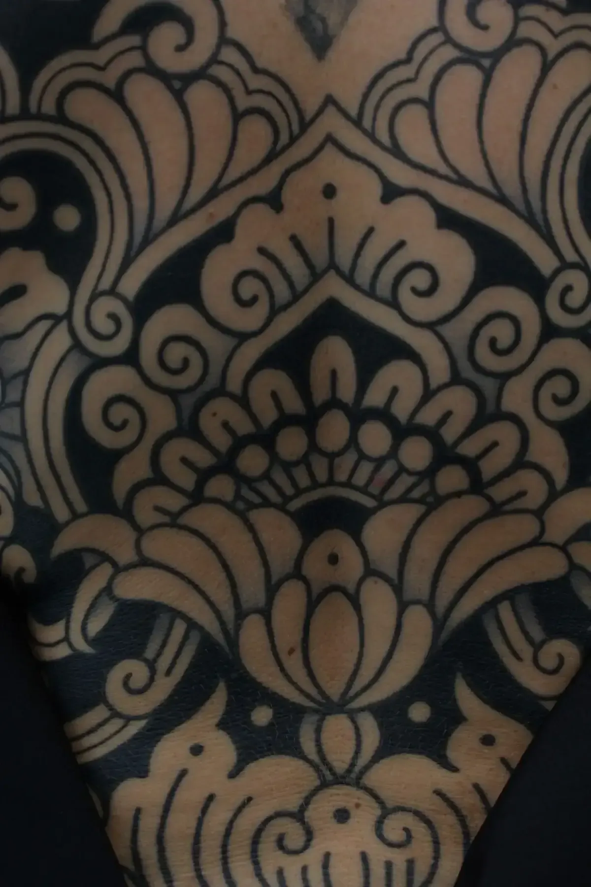 Primer plano de un tatuaje que presenta un diseño ornamentado y simétrico con patrones en espiral.
