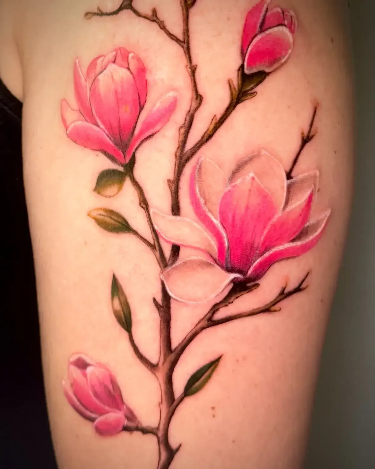 Tatuaje de flor de magnolia rosa en el brazo.