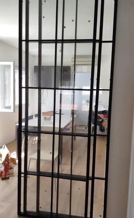 Puerta corredera interior de vidrio y metal negro. La puerta divide dos estancias.
