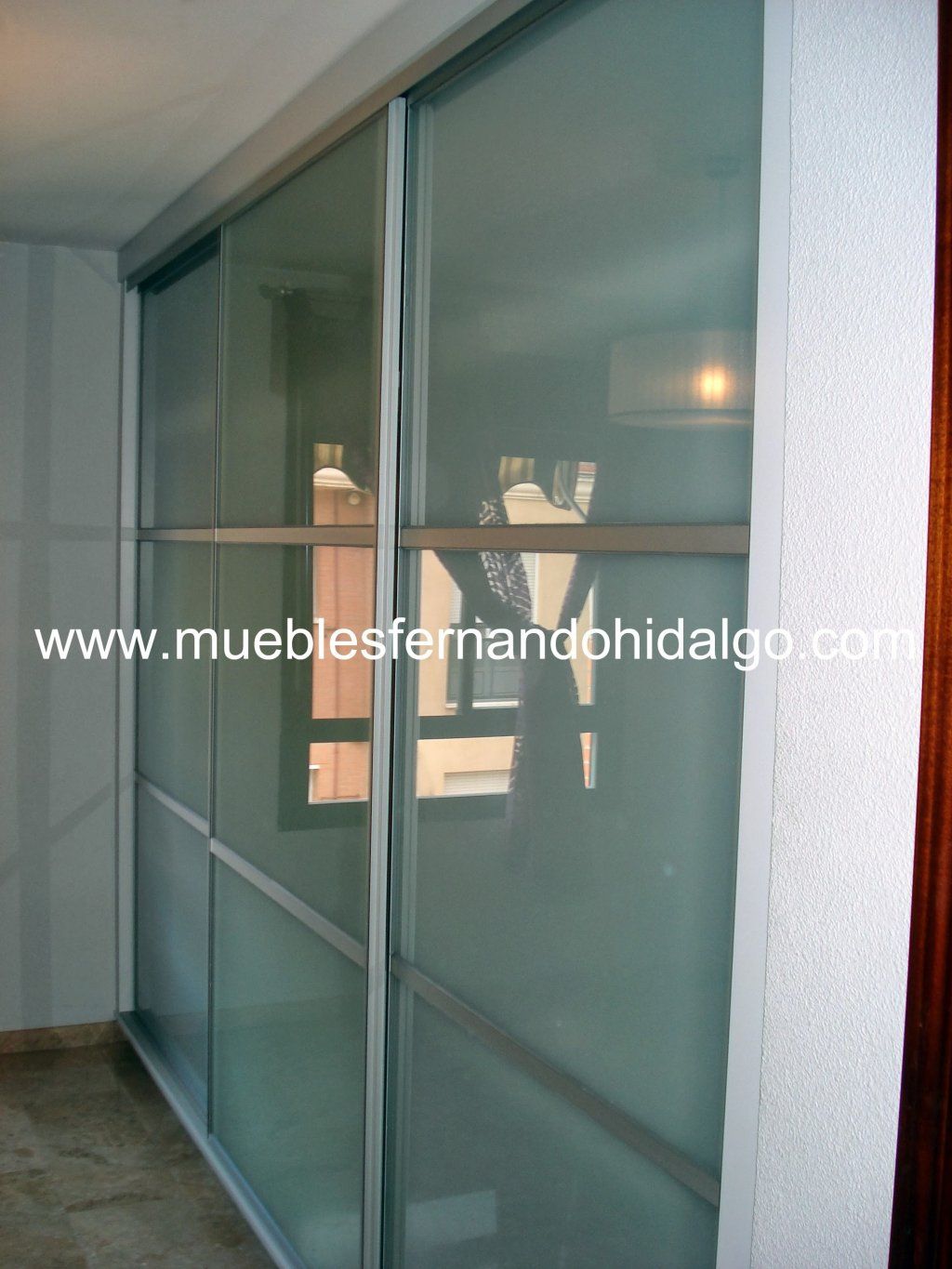 Una puerta corrediza de cristal con la web www.mueblesfernandohidalgo.com