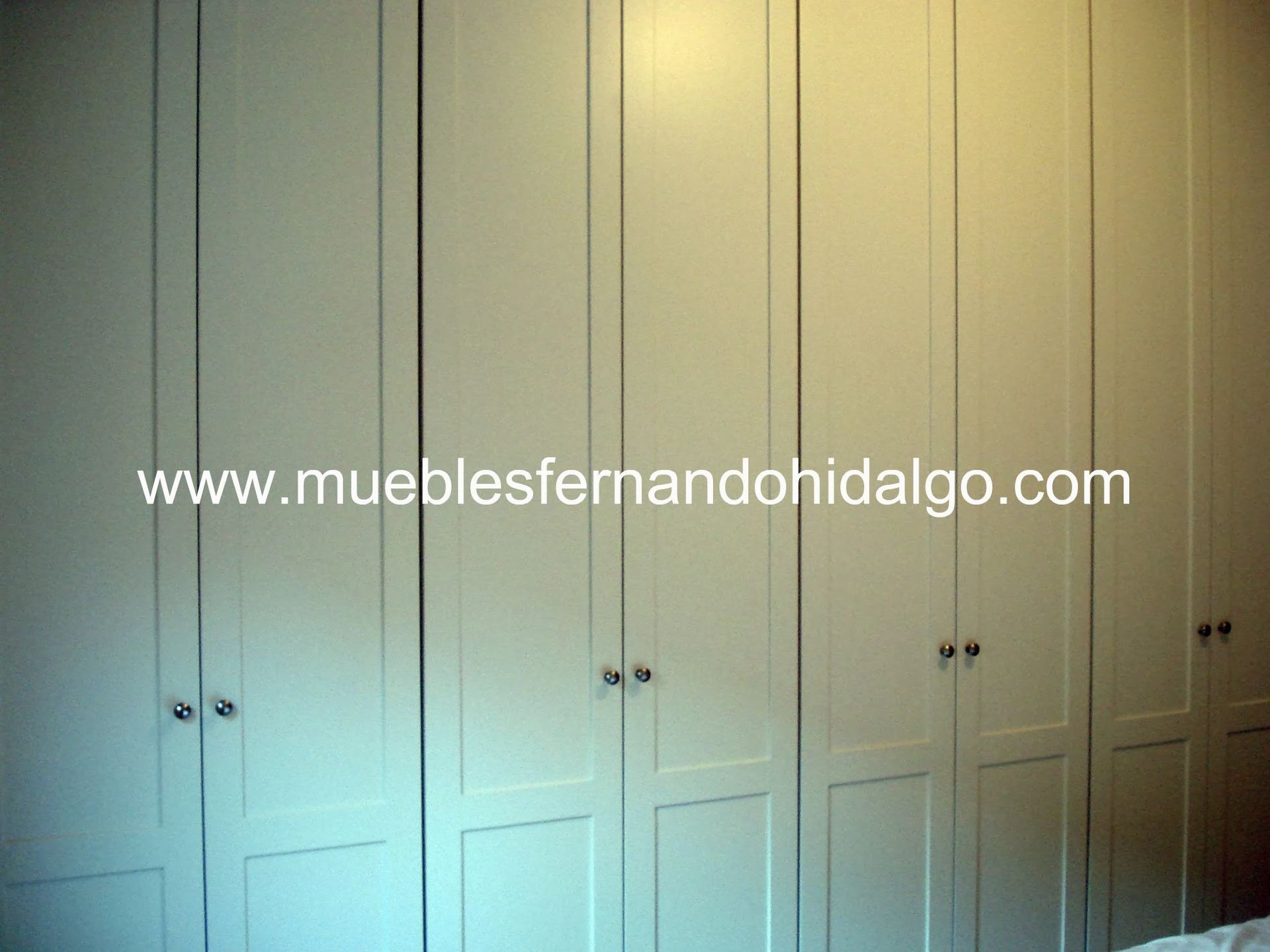 Una fila de armarios blancos con la página web www.mueblesfernandohidalgo.com en la esquina