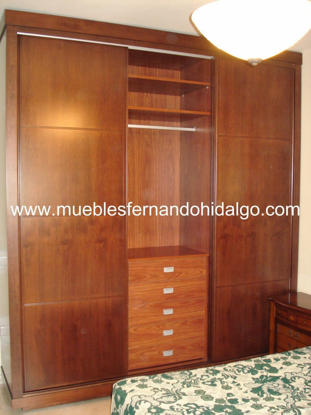 Un dormitorio con un gran armario de madera y la web www.mueblesfernandohidalgo.com