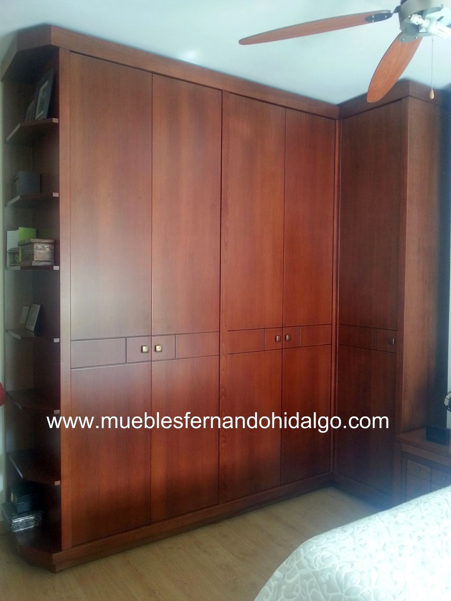 Un dormitorio con un gran armario de madera y un ventilador de techo.