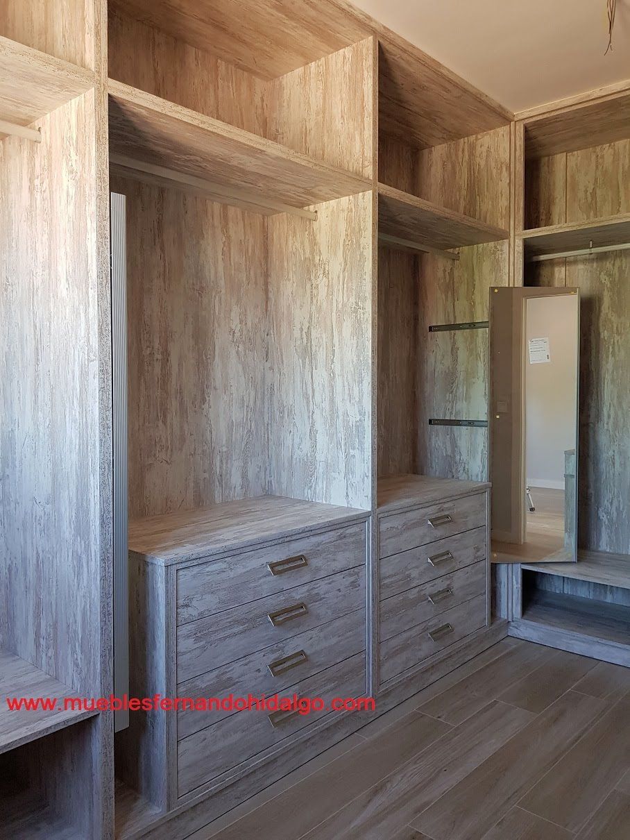 Un vestidor con muchos estantes y cajones y un espejo.