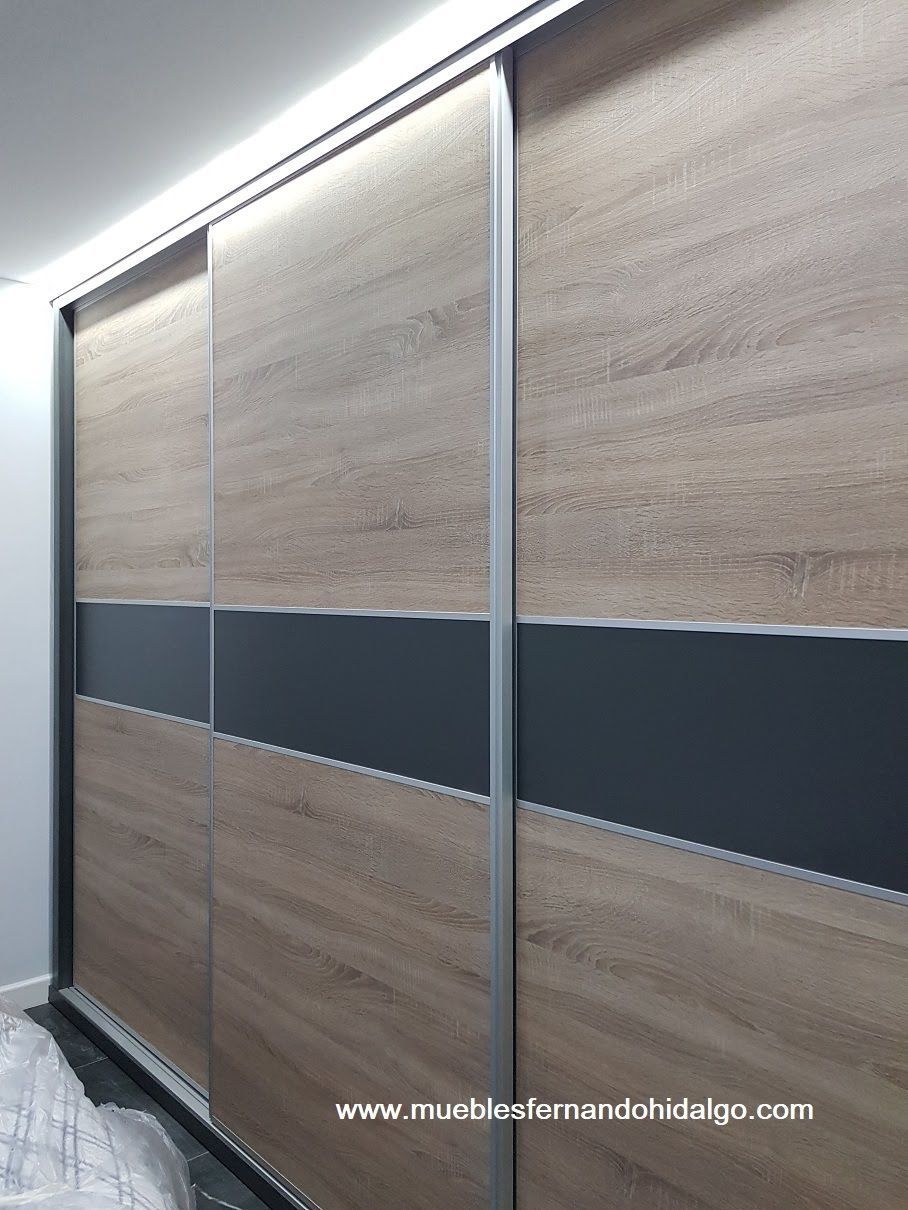 Un armario con puertas correderas fabricado en madera y con una raya negra.