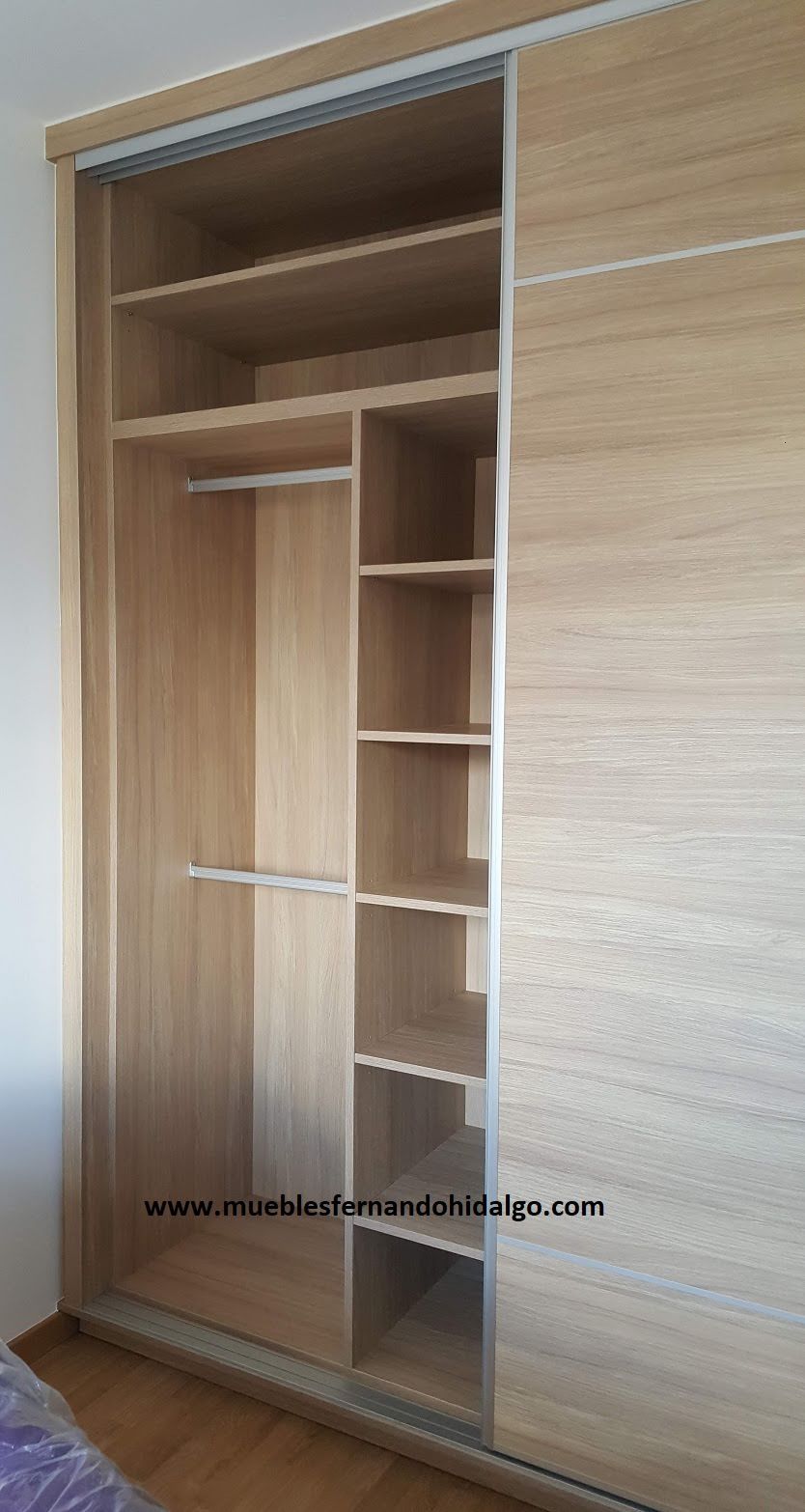 Un armario de madera con puertas correderas y estantes en un dormitorio.