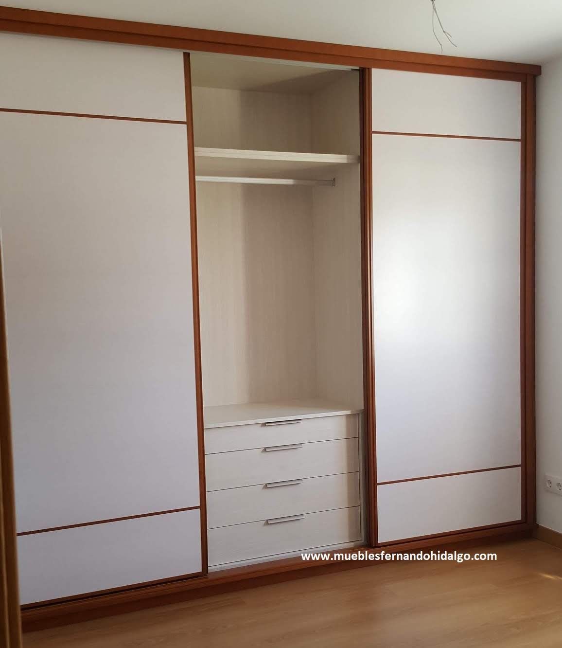 Un gran armario blanco con puertas correderas y cajones.