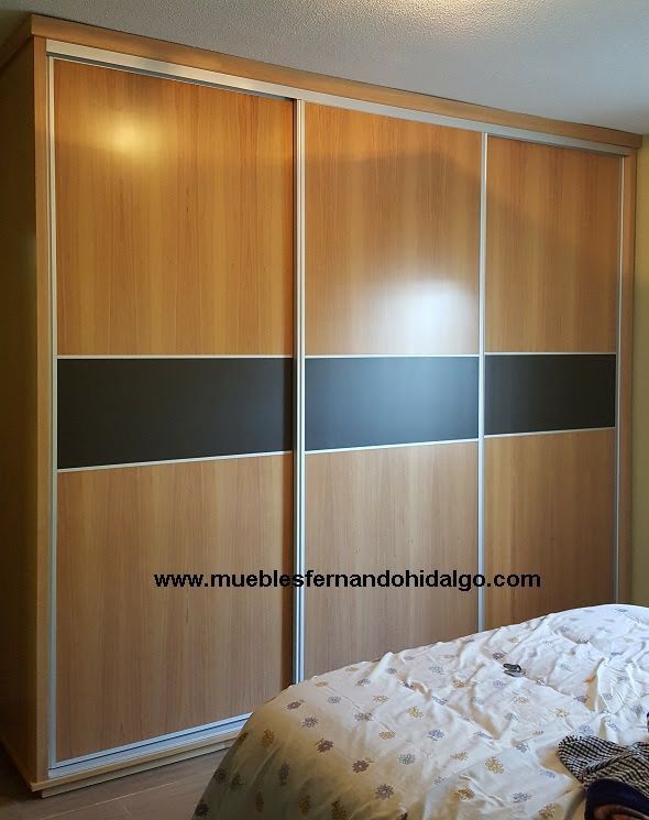 Un dormitorio con armario de puertas correderas y la web www.mueblesfernandohidalgo.com