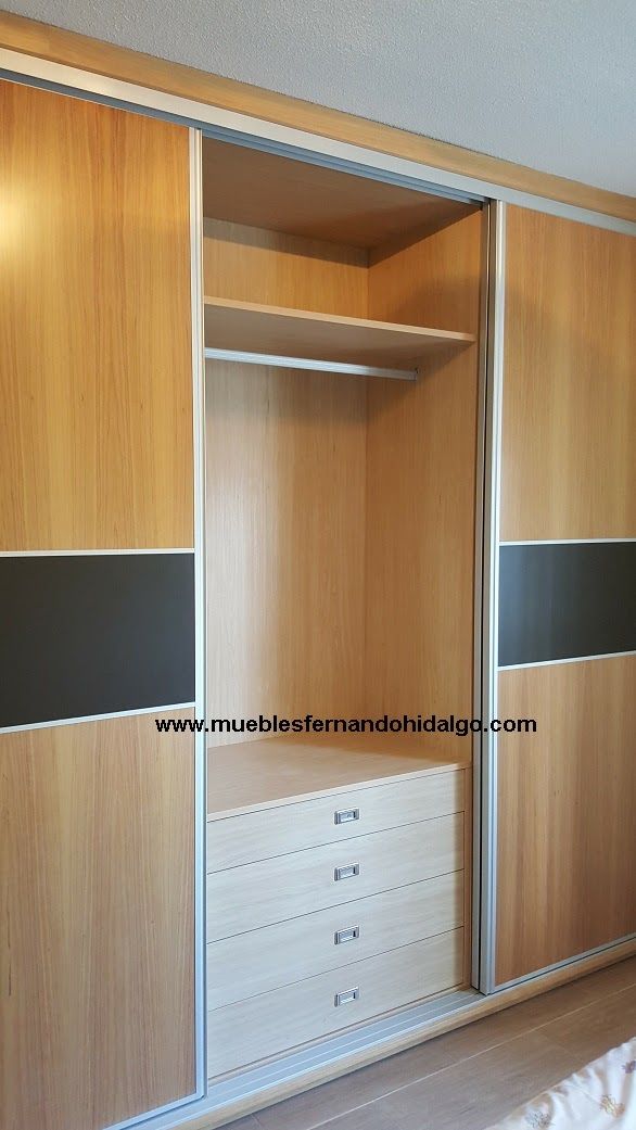 Un armario con puertas correderas y cajones en un dormitorio.