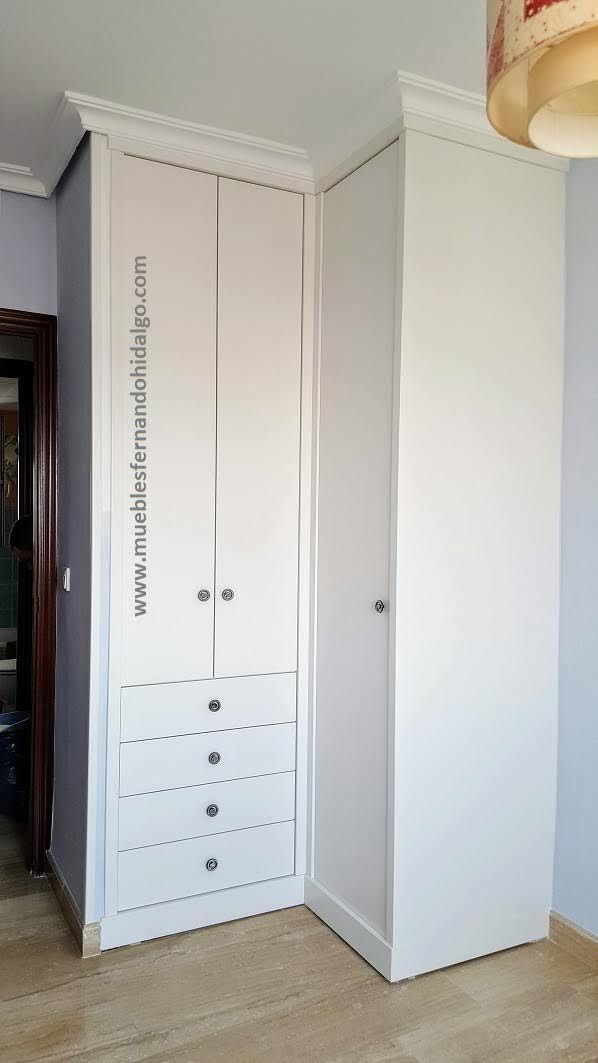 Un armario de esquina blanco con cajones y puertas en un dormitorio.