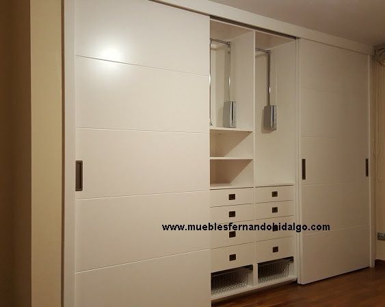 Un gran armario blanco con puertas correderas y cajones.