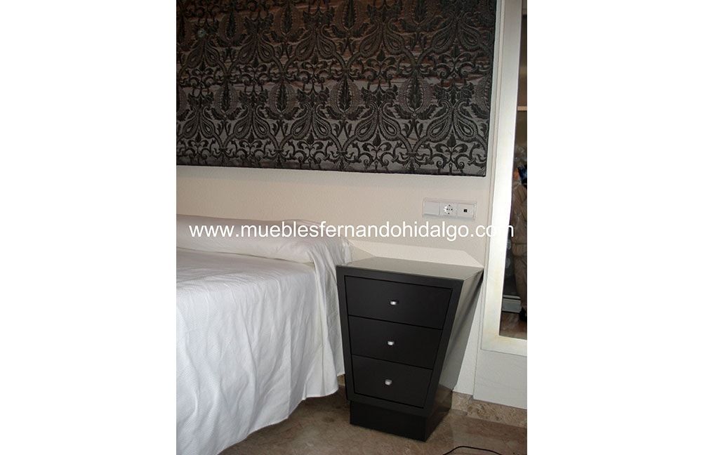 Un dormitorio con cama, mesita de noche y cómoda.