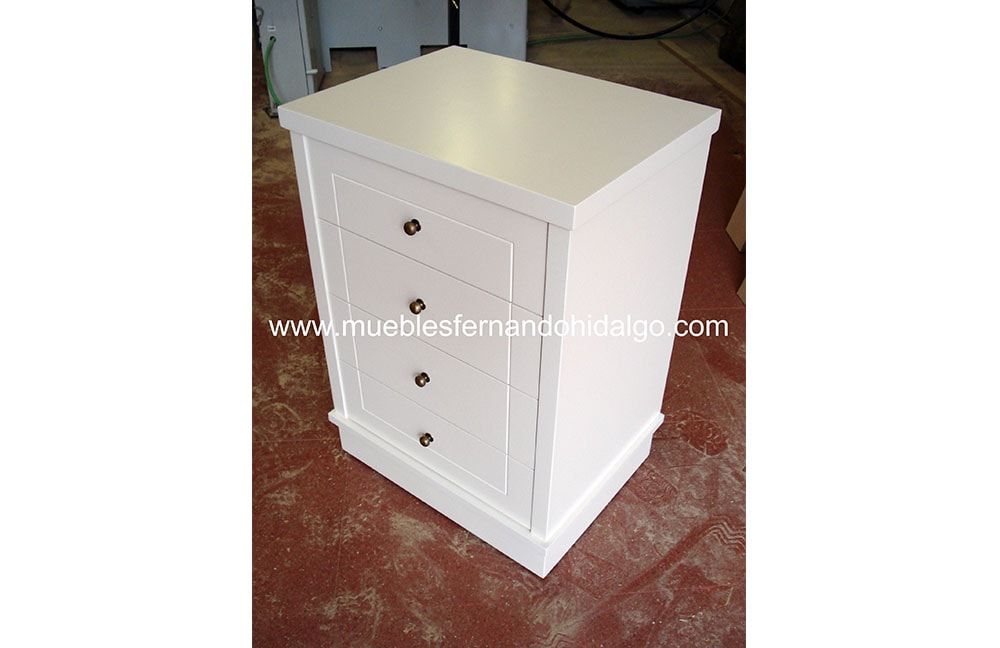 Una pequeña mesita de noche blanca con tres cajones y una puerta.