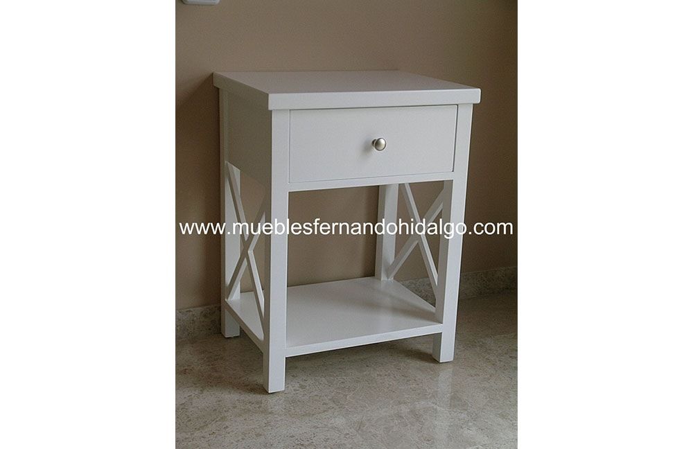 Una pequeña mesita de noche blanca con cajón y estante.