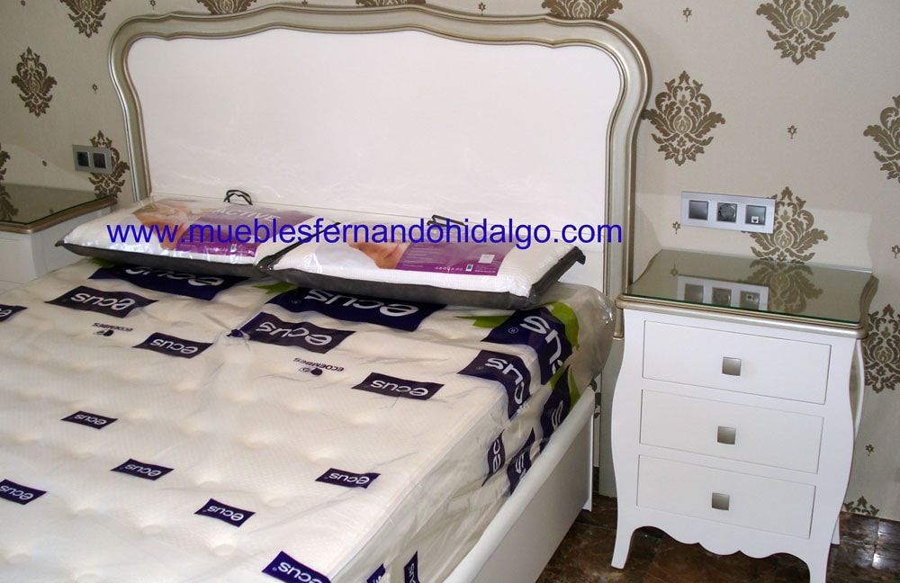 Una cama con colchón y mesita de noche con la página web www.mueblesfernandohidalgo.com en la esquina