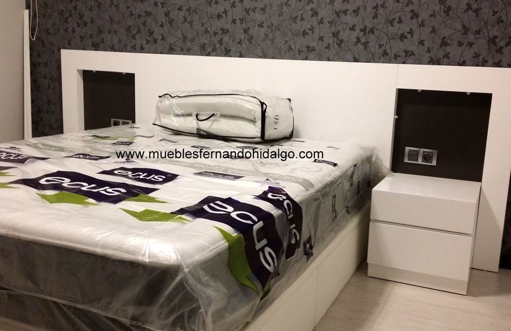 Una cama con un colchón y dos mesitas de noche en un dormitorio.