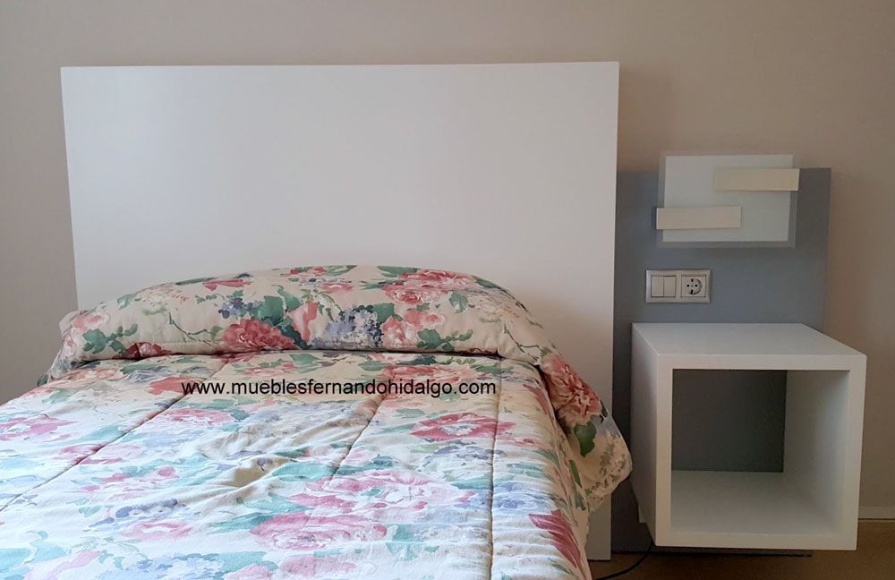 Una cama con un edredón floral y una mesita de noche en un dormitorio.