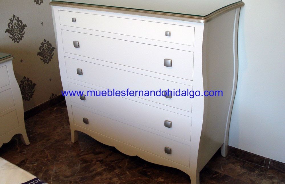 Una cómoda blanca en un dormitorio con la web www.mueblesfernandohidalgo.com