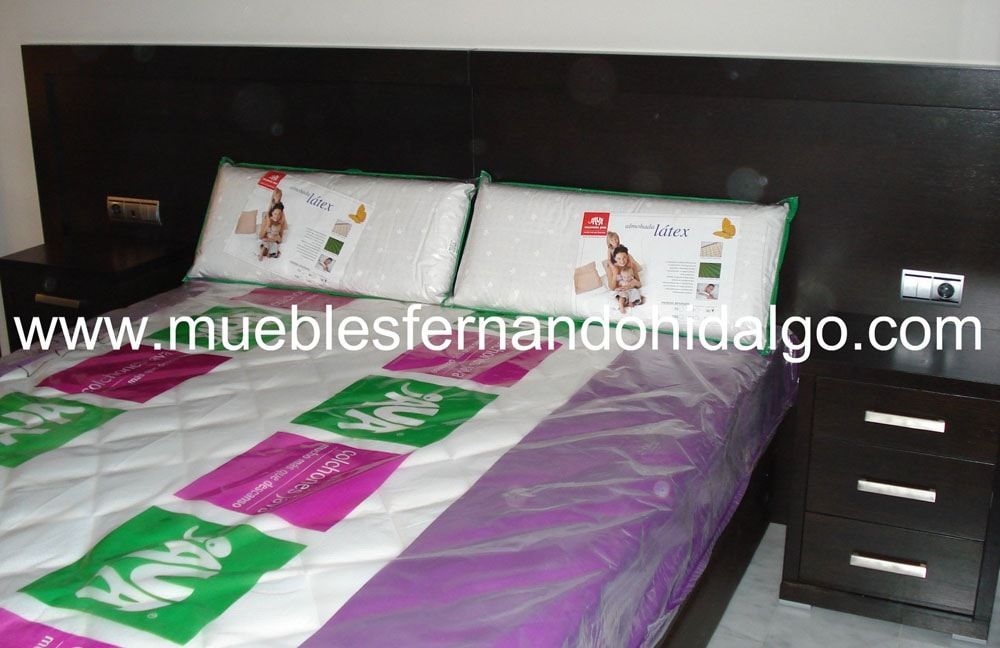 Una cama con una manta y almohadas moradas y verdes.