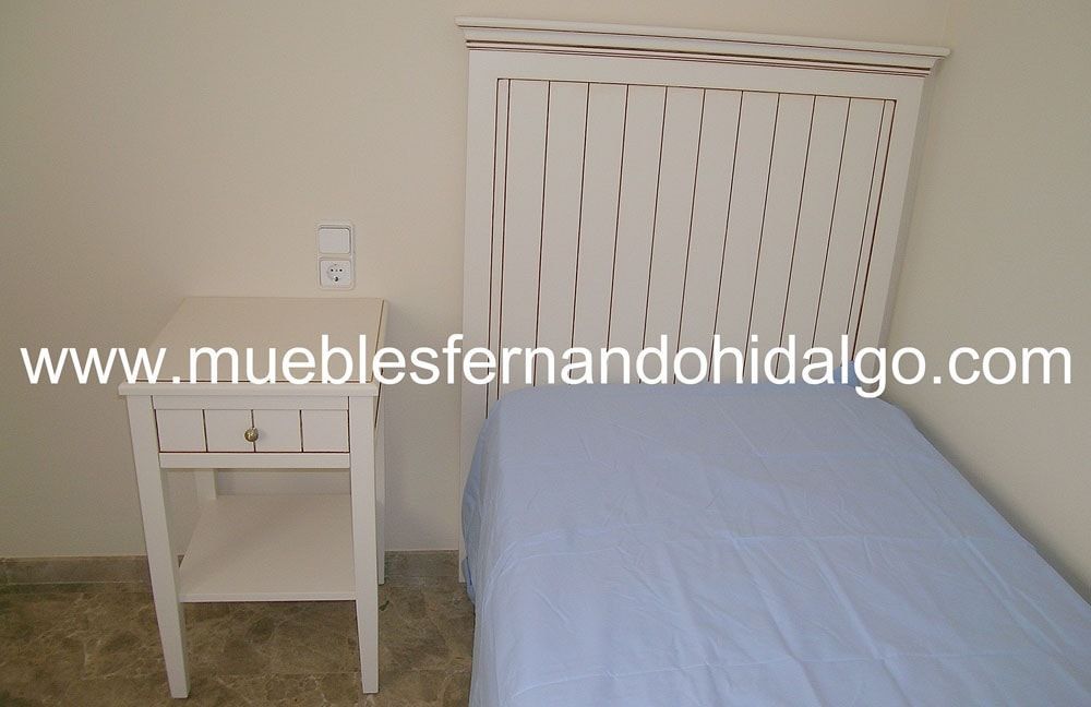 Un dormitorio con cama y mesita de noche y la página web www.mueblesfernandohidalgo.com