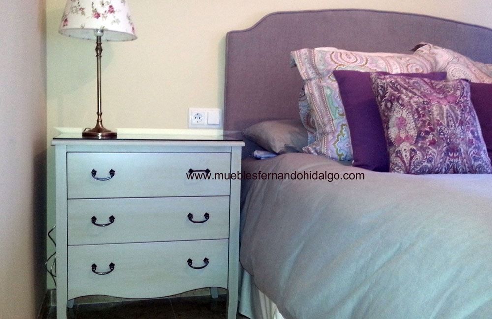 Un dormitorio con una cama, una mesita de noche y una lámpara.