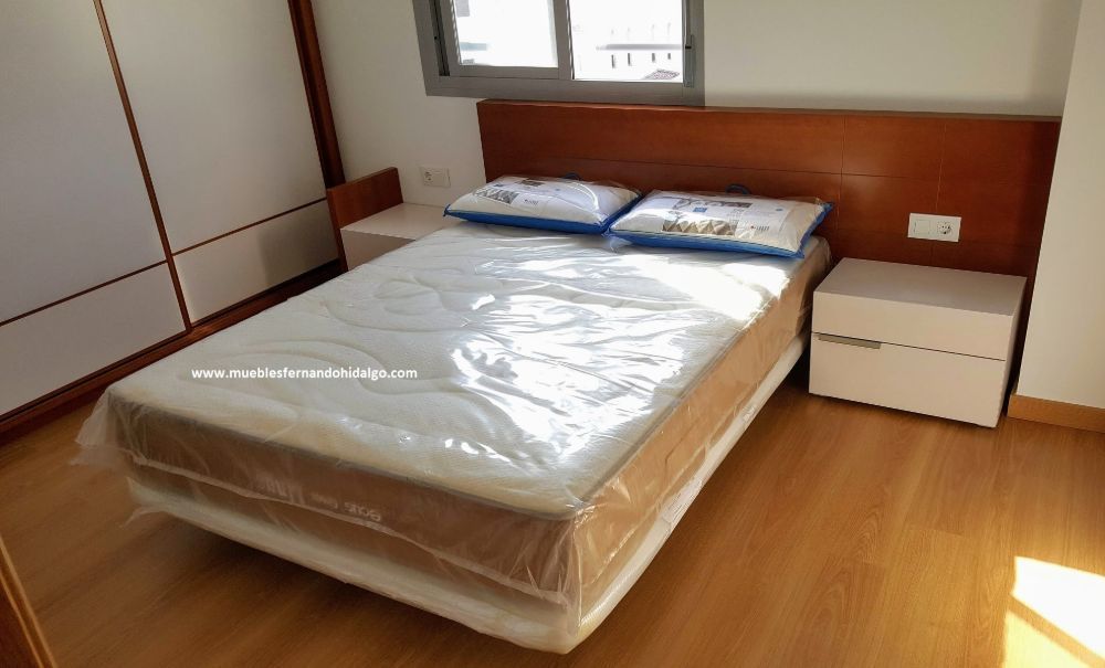 Una cama con un colchón y dos mesitas de noche en un dormitorio.
