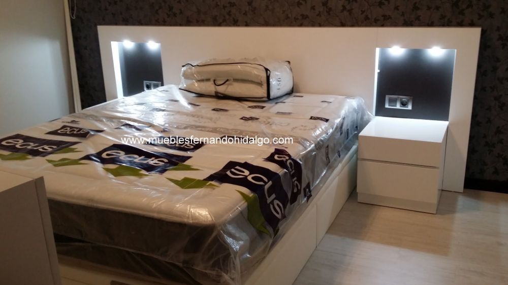 Una cama con un colchón y dos mesitas de noche en un dormitorio.