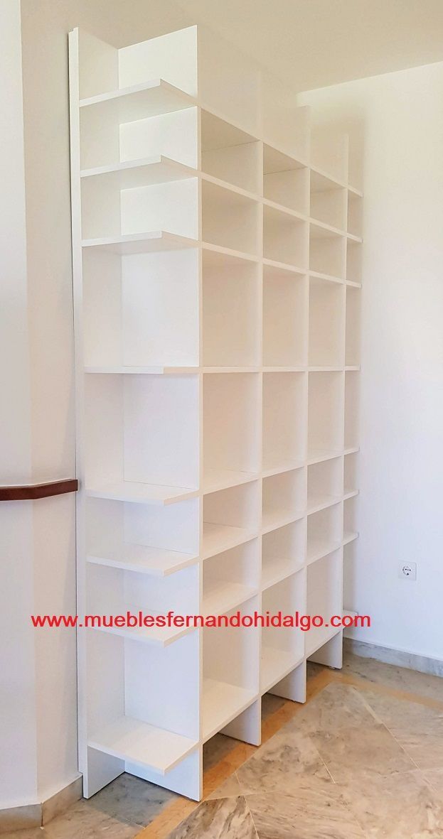 Una estantería blanca se encuentra en un rincón de una habitación.
