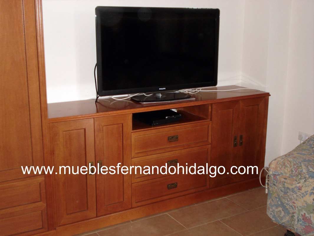 Un televisor de pantalla plana está sobre un centro de entretenimiento de madera.