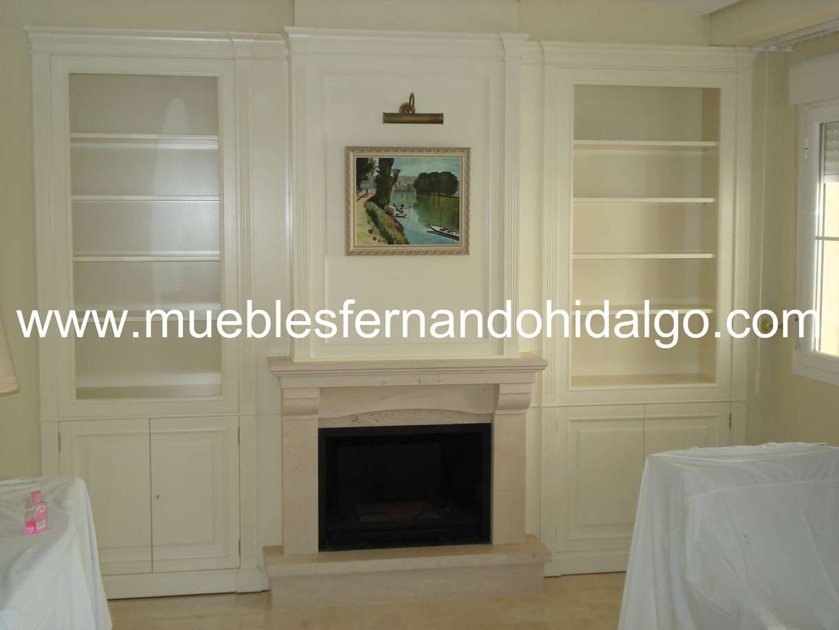 Un salón con chimenea y estanterías con la web www.mueblesfernandohidalgo.com