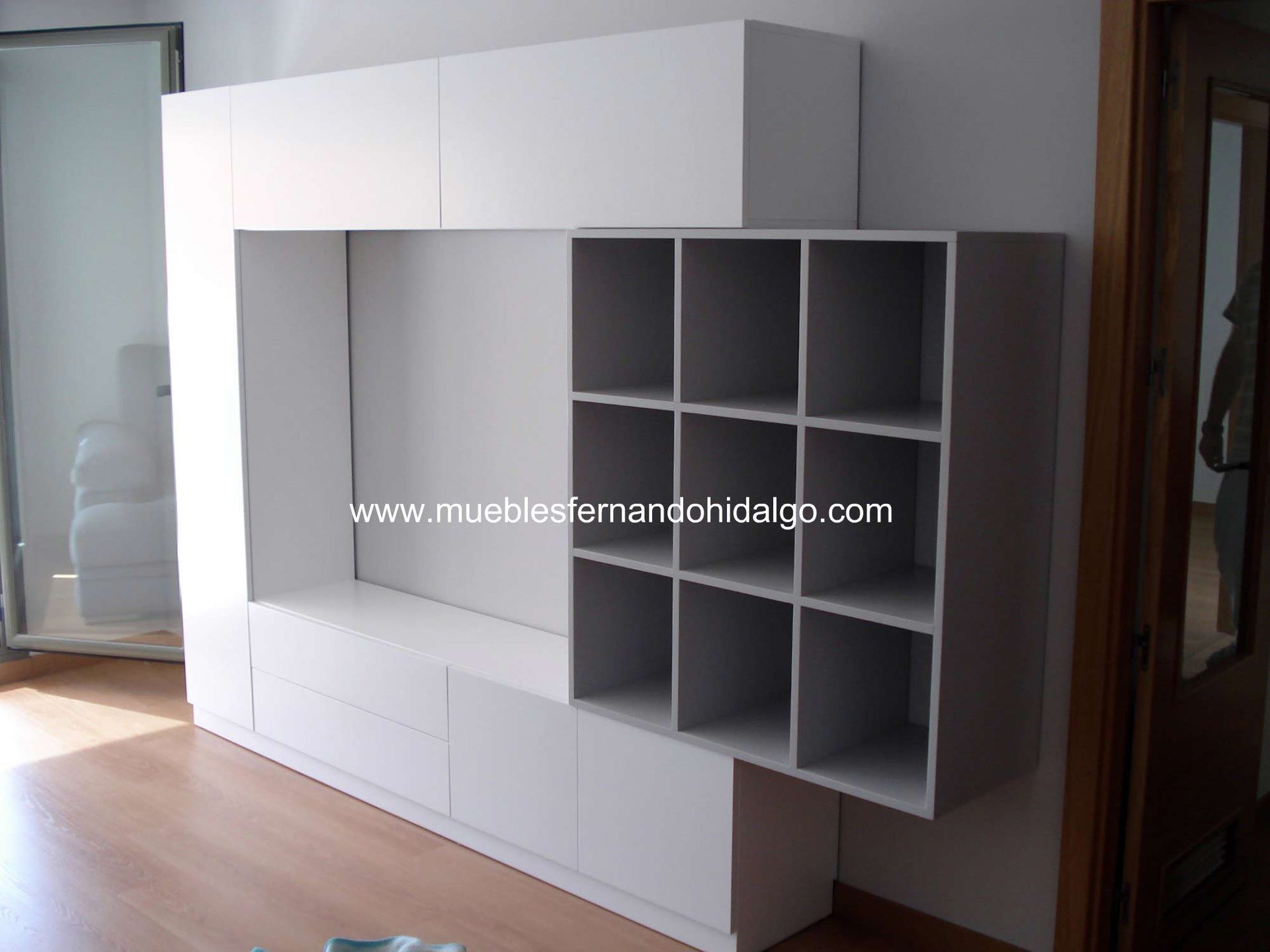 Una estantería blanca con la página web www.mueblesfernandohdaigo.com
